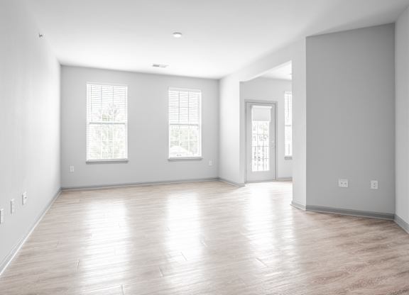 A large empty room with wooden floors and windows.