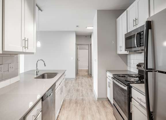 A modern kitchen with stainless steel appliances and wooden floors.