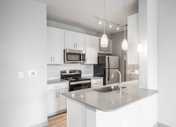 A modern kitchen with a stainless steel sink and white cabinets.