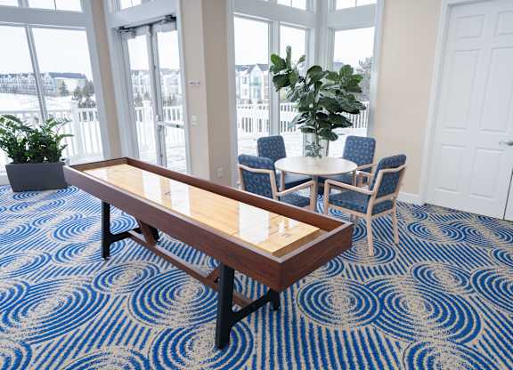 A room with a blue carpet and a wooden table at The Harbours Apartments, Clinton Twp