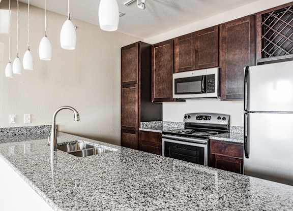 A kitchen with a granite countertop and stainless steel appliances.