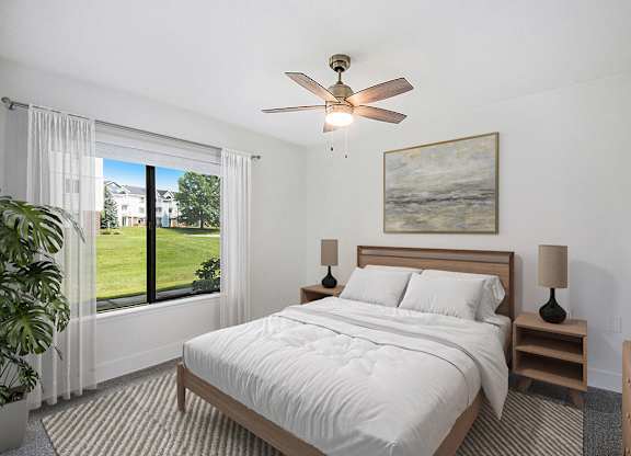 a bedroom with a bed and a ceiling fan and a window at The Crossings Apartments, Michigan, 49508