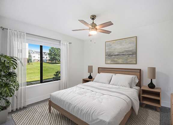 A bedroom with a large bed, a ceiling fan, and a large window at Byron Lakes Apartments, Michigan, 49315