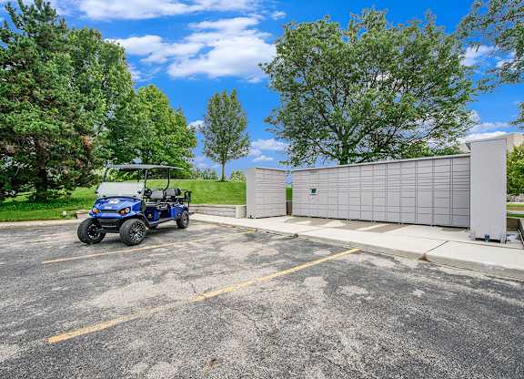 A blue golf cart is parked next to Amazon Hub package lockers at The Crossings Apartments in Grand Rapids, MI