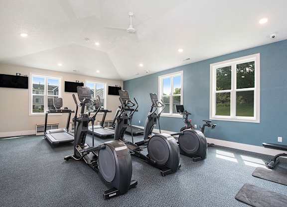 fitness center with plenty of cardio equipment and windows at The Crossings Apartments, Michigan, 49508
