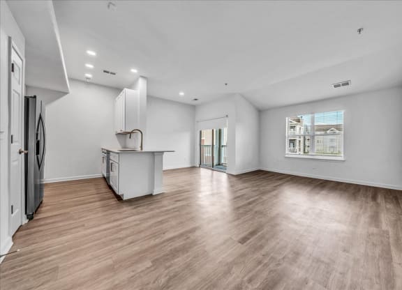 an empty living room with a kitchen and a large window at The Vinings Apartments in Richmond, VA 23234