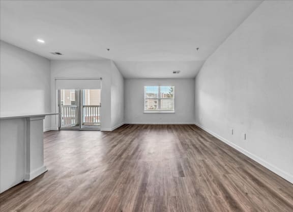 an empty living room with wood flooring and a balcony at The Vinings Apartments in Richmond, VA 23234