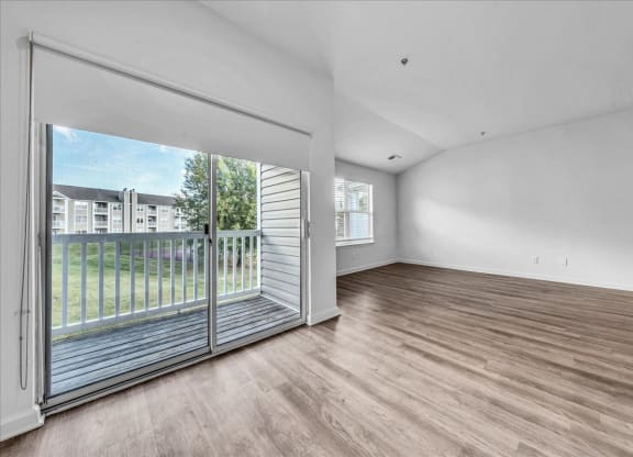 a living room with a sliding glass door to a balcony at The Vinings Apartments in Richmond, VA 23234