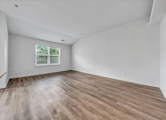 the living room of an empty home with wood flooring at The Vinings Apartments in Richmond, VA 