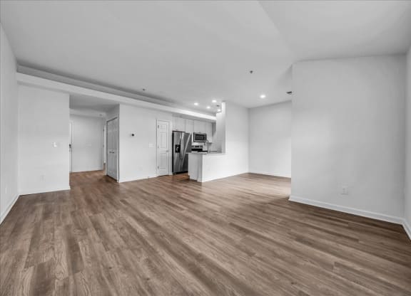 the living room and kitchen of a new home with white walls and wood floors at The Vinings Apartments in Richmond, VA 