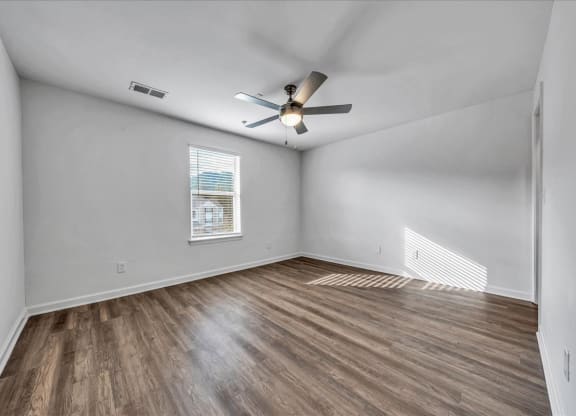 an empty living room with a ceiling fan and a window at The Vinings Apartments in Richmond, VA 
