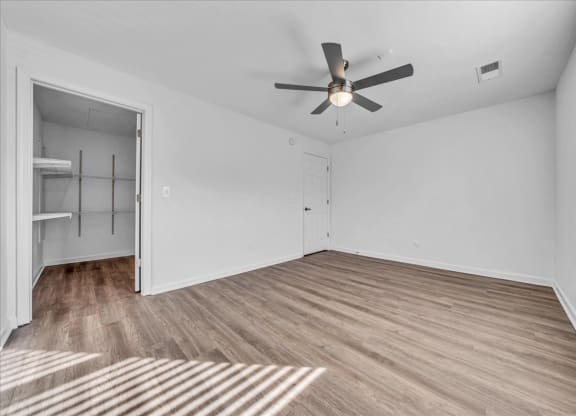 an empty living room with a ceiling fan and a closet at The Vinings Apartments in Richmond, VA 