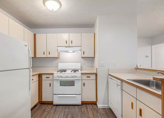 A kitchen with white appliances and wooden cabinets at Tracy Creek Apartments, Ohio