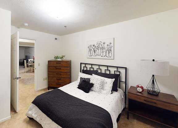 A bedroom with a bed, nightstand, and lamp at Tracy Creek Apartment Homes in Perrysburg, OH