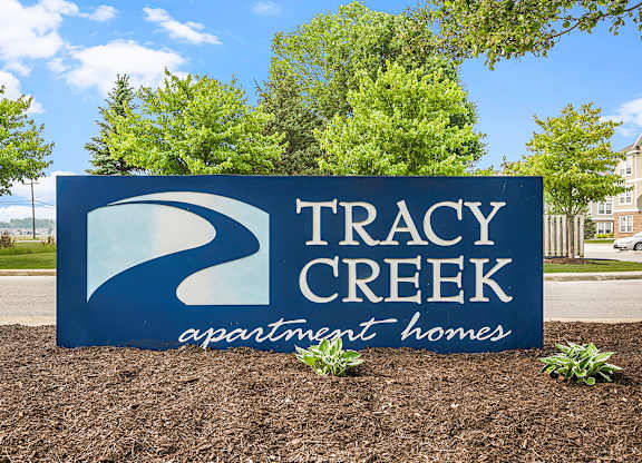 A sign for Tracy Creek Apartment Homes is displayed in front of a building.