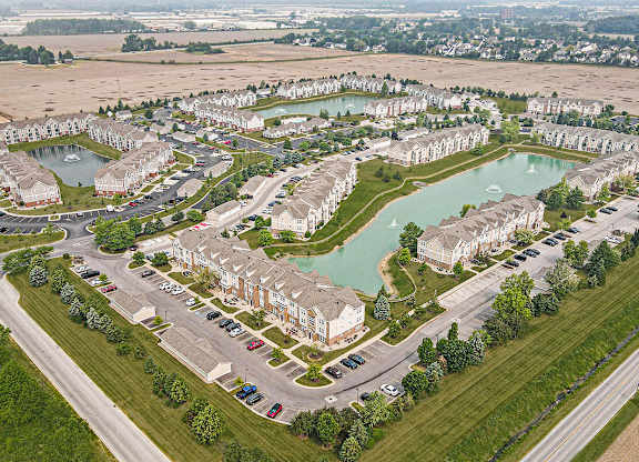 A bird's eye view of a residential area with a pond and apartment buildings at Tracy Creek Apartments, Perrysburg