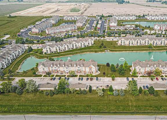 A large aerial view of an apartment complex with a pond in the middle at Tracy Creek Apartments, Perrysburg