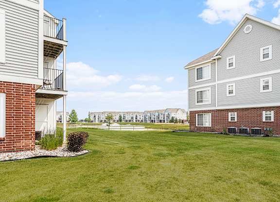 A grassy area with a pond behind apartment buildings at Tracy Creek Apartments, Perrysburg