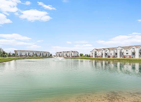 A large body of water with a fountain in the middle and apartment buildings in the background at Tracy Creek Apartments, Perrysburg