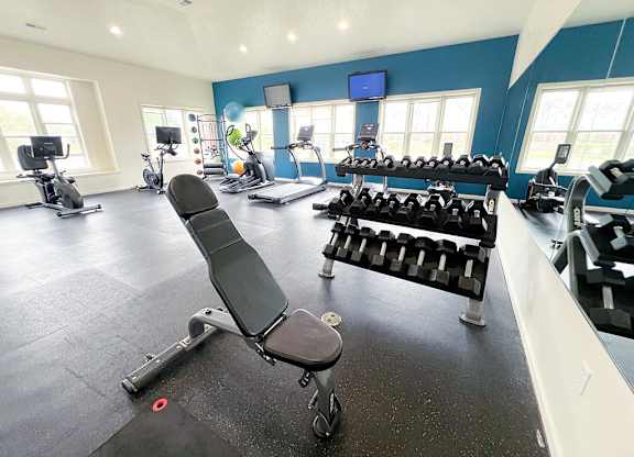 A gym with a variety of equipment including weights and cardio machines at Tracy Creek Apartments, Perrysburg, OH, 43551