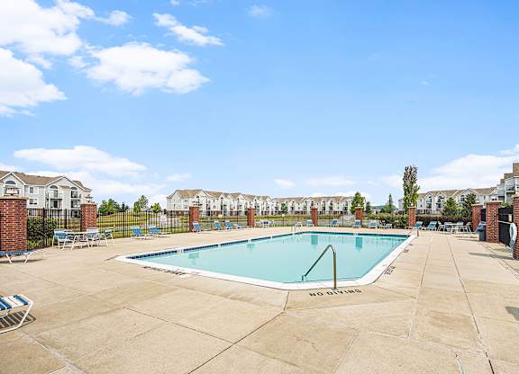 A large swimming pool with Wi-Fi surrounded by a concrete patio and a fence at Tracy Creek Apartments, Perrysburg