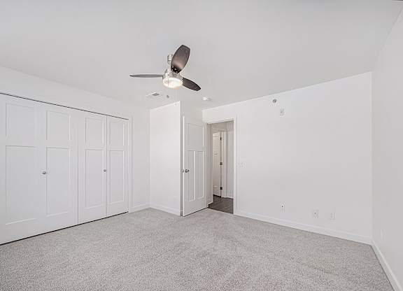 A room with a ceiling fan and carpeted floor.