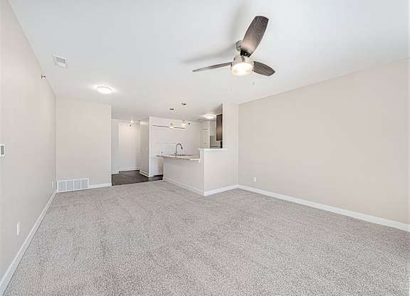 A room with a ceiling fan and carpeted floor.