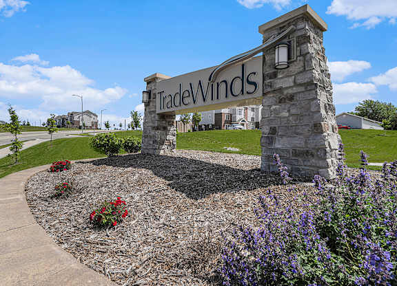 entrance sign with landscaped flowers at Trade Winds Apartment Homes in Elkhorn, NE 68022