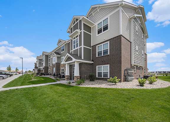 apartment building with grass and sidewalks at Trade Winds Apartment Homes in Elkhorn, NE 68022