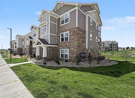 A large, modern apartment building with a well-maintained lawn in front at Trade Winds Apartment Homes, Elkhorn, NE, 68022