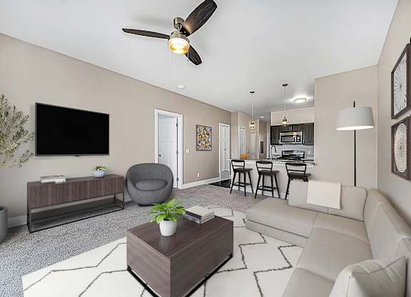 A living room with a grey armchair, a white sofa, a wooden coffee table, and a ceiling fan at Trade Winds Apartment Homes, Elkhorn, Nebraska
