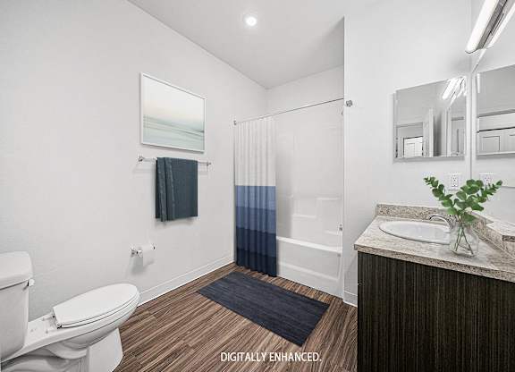 A main bathroom with a toilet, sink, and mirror at Trade Winds Apartment Homes, Elkhorn, Nebraska
