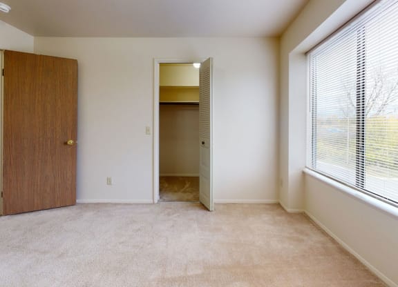 a bedroom with a large window and a door to a closet  at Trappers Cove Apartments, Michigan