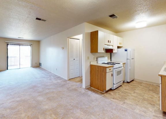 galley style kitchen and living room with a slider to a balcony at Trappers Cove Apartments, Michigan, 48910