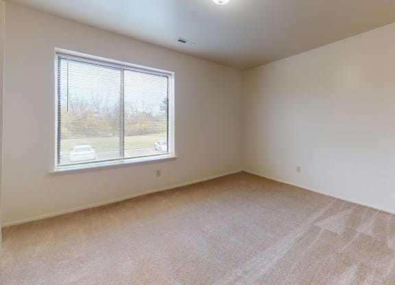 bedroom with a window and carpet at Trappers Cove Apartments, Lansing