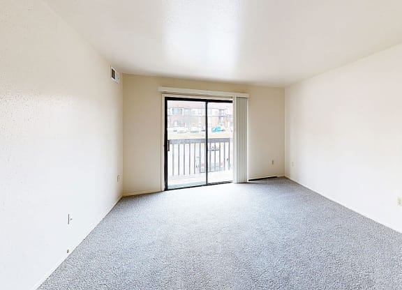 an empty living room with a door to a balcony  at Trappers Cove Apartments, Lansing, MI, 48910