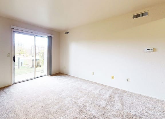 living room with a sliding glass door to a private patio at Trappers Cove Apartments, Michigan
