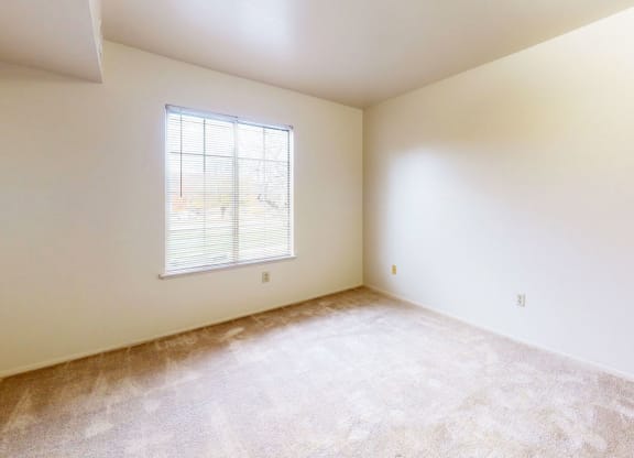 a large bedroom with carpet and a window at Trappers Cove Apartments, Lansing, MI, 48910