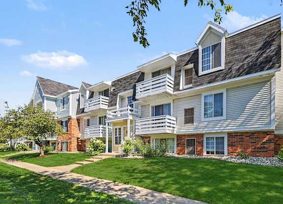 An apartment building with a green lawn in front at Trappers Cove Apartments, Lansing, 48910
