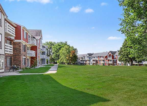 A green lawn behind an apartment building at Trappers Cove Apartments, Lansing, 48910
