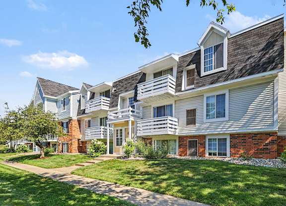 An apartment building with a clear blue sky above at Trappers Cove Apartments, Lansing, MI, 48910