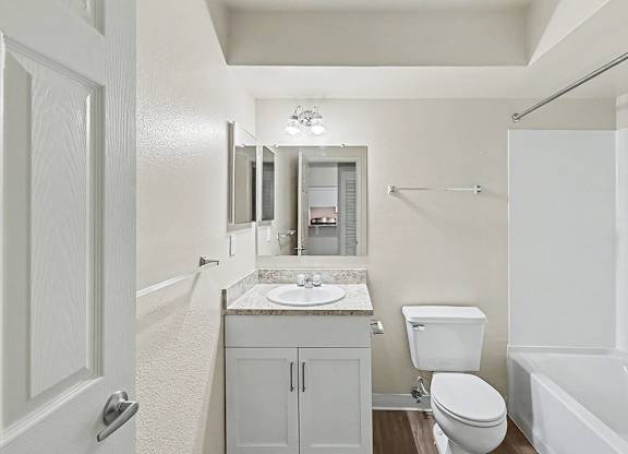 An upgraded bathroom with a toilet, sink, and bathtub at Trappers Cove Apartments, Lansing