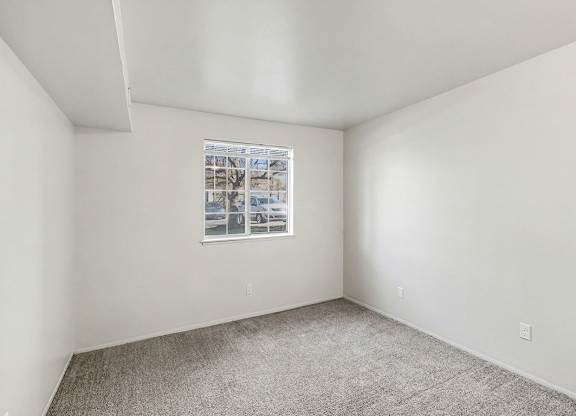 Large bedroom with a window and plush carpeting at Trappers Cove Apartments, Lansing, MI, 48910
