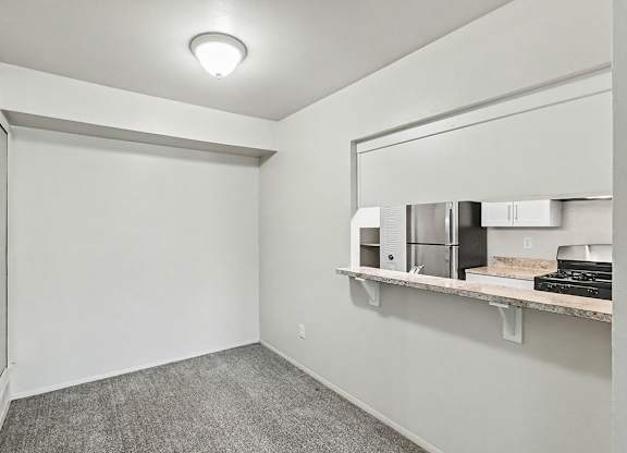 A dining room with a grey carpet and a breakfast bar at Trappers Cove Apartments, Lansing
