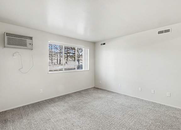 A garden style living room with a window showing trees outside at Trappers Cove Apartments, Lansing
