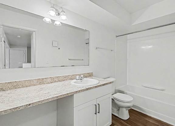 An upgraded bathroom with a sink, mirror, and bathtub at Trappers Cove Apartments, Lansing, Michigan
