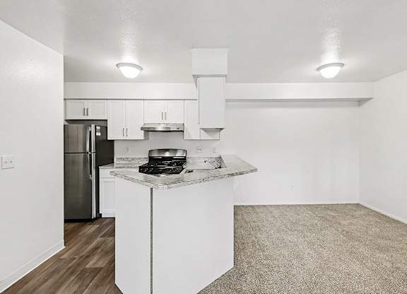 A kitchen with white cabinets and a breakfast bar at Trappers Cove Apartments, Lansing