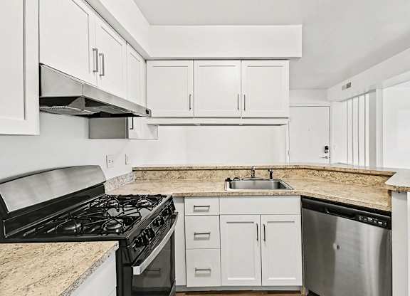 A kitchen with stainless steel appliances and white shaker-style cabinets at Trappers Cove Apartments, Lansing