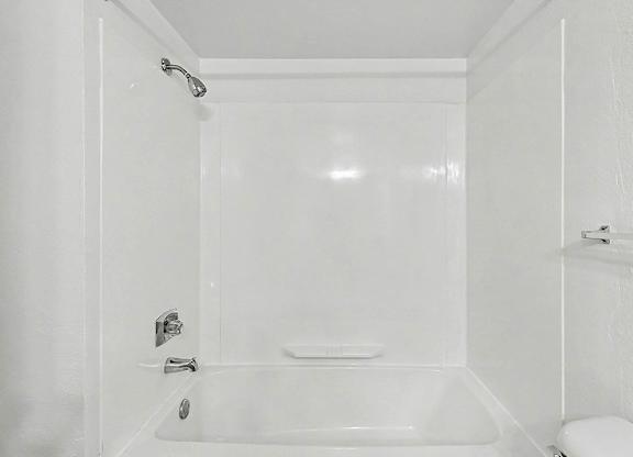 A white bathroom with a bathtub and toilet at Trappers Cove Apartments, Lansing