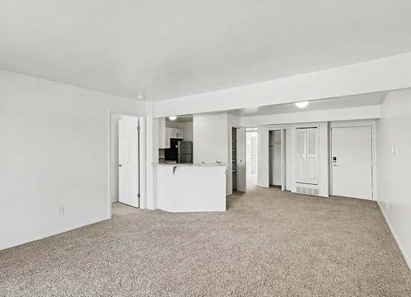 A spacious living room with carpeting and a breakfast bar at Trappers Cove Apartments, Lansing